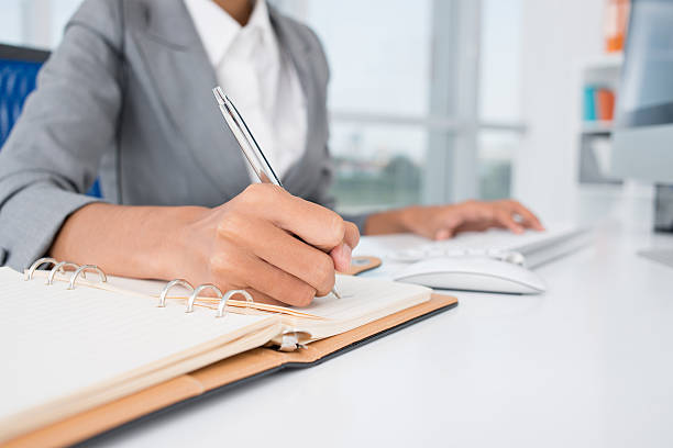 close up of female hands making notes in the notepad at office
